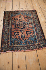 Corner of Borchalou rug with geometric floral border and red-tinted tattered fringe.