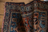 Piled texture of vintage Borchalou rug; rust, navy, teal geometric floral motifs; blush fringe.