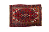 Vintage Heriz rug, cherry red field with diamond medallion and gem-tone floral motifs.