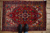 Vintage Heriz rug displaying multi-colored pearl borders and vibrant jewel-tone floral motifs.