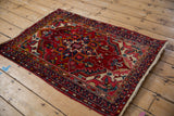 Vintage Heriz rug corner with multi-colored pearl borders and cherry red field.