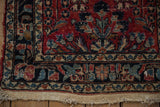 Vintage Lilihan rug corner, textured pile, red and navy patterns, exposed foundation edge.