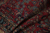 Vintage Lilihan runner folded, revealing cherry red floral vinery, navy blue motifs, and pile wear.