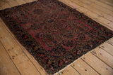 Lilihan rug detail: dusty dark raspberry field, paisley plants, navy, gold, worn edges.