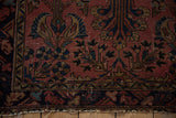 Vintage Lilihan rug corner showcasing dusty raspberry field, paisley plants, and tattered end fringe.