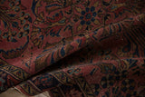 Detail of vintage Lilihan rug's tattered side, with navy and raspberry paisley motifs.