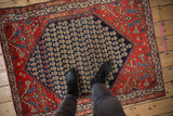 A perspective view for scale of a vintage Malayer rug, showing the navy boteh field and red spandrels.