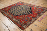 Corner view of a vintage Malayer rug with a navy boteh field and detailed red spandrels.