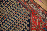 Visible knot heads and wool pile at the corner of a vintage Malayer with navy and red motifs.