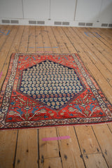 Angled view of a vintage Persian Malayer rug, showing the full boteh and spandrel design.
