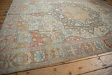 Distressed Malayer carpet corner: fringed edge, muted ivory, red, blue floral patterns.