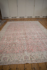 Faded pink field of a distressed vintage Sparta carpet, showcasing scrolling vinery.