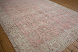 Distressed pink and beige Turkish Sparta rug with faded floral vinery and patterned border.