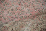 Textured pile and faded pink field with beige scrolling vinery on a distressed Sparta carpet.