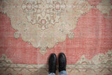 Distressed Turkish Sparta carpet detail, featuring blush, ivory medallion with arabesque motifs.