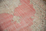 Distressed blush field with ivory scrolling arabesques and foundation wear on a vintage Sparta rug.