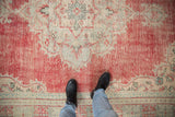 Detail of vintage distressed Oushak rug, with faded cherry red, ivory, and dusty turquoise pile.