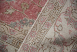 Distressed vintage Sparta carpet: softened hand-knotted pile texture in dusty raspberry, ivory, and pale brown.