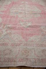 Distressed vintage Sparta carpet with worn pink pile and faded ivory border patterns.