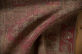 Low pile distressed vintage rug showing faded pink and brown geometric motifs.
