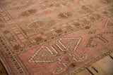 Plush, distressed Bokhara rug with dusty rose, coffee brown geometric gul, visible fringe.