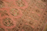 Distressed Bokhara rug's rose abrashed field and coffee brown geometric gul motifs.