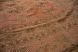 Distressed dusty rose Bokhara carpet pile showing geometric gul patterns and abrashed field.