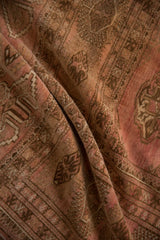 Soft plush pile texture and dusty rose, brown gul motifs on a distressed Bokhara rug.