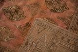 Distressed Bokhara carpet showing hand-knotted foundation and dusty rose elephant footprint design.