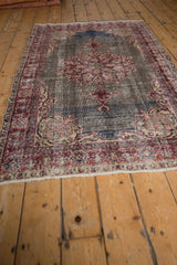 Artfully distressed vintage Sparta rug pile, showing faded cherry red motifs on abrashed gray-blue field.