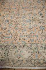 Distressed pale apricot field and ivory border displaying muted floral patterns on the Sparta rug.