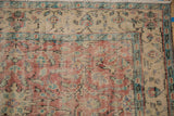 Distressed Oushak carpet pile detail, revealing worn foundation with faded red, ivory, blue, and green motifs.