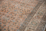 Faded terracotta field of a distressed vintage Turkish Sparta carpet with sky blue floral motifs and ivory border.