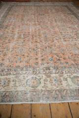 Worn low pile and faded floral motifs on the ivory border and pale terracotta field.