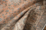 Distressed vintage Sparta carpet showing folded terracotta, ivory, and blue flower motifs.