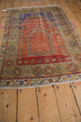 Distressed vintage Melas prayer rug showcasing terracotta field, royal blue mehrab, and worn floral borders.