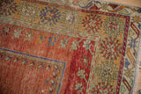 Distressed vintage Turkish Melas rug corner showcasing rich terracotta, saffron, and royal blue floral borders.