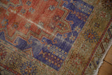 Textured vintage Melas rug showing royal blue mehrab, terracotta field, and abrash with fringe.