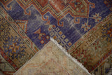 Worn pile of vintage distressed Melas rug in royal blue, terracotta, ivory, revealing woven back and fringe.