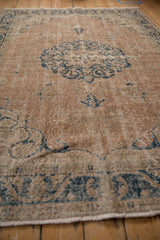 Distressed vintage Turkish Sparta rug texture, faded navy blue floral motifs, worn ivory pile.