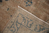 Distressed vintage Sparta carpet corner, revealing hand-knotted reverse, fringe, and dusty navy design.