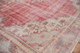 Worn cherry red field meets an ivory border featuring pale rose floral vinery on a vintage Oushak.