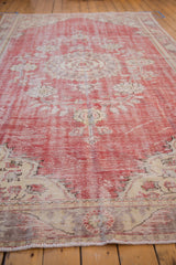 Distressed vintage Oushak carpet, worn cherry red pile with faded ivory floral motifs.