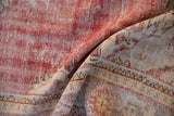 Distressed Oushak carpet pile featuring muted red, ivory tones and visible knot heads.