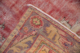 Distressed red field with visible foundation and patterned corner of a vintage Oushak.