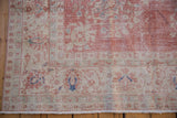 Distressed vintage Sparta rug, showing wear to foundation, with faded pink and blue motifs.