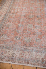 Distressed hand-knotted texture with faded floral vinery in dusty terracotta and ivory tones.