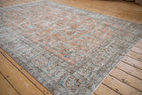 Distressed vintage Sparta carpet corner, faded apricot field, ivory border, sky blue florals.