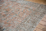 Distressed vintage Sparta carpet's worn apricot, ivory, and sky blue floral motifs.