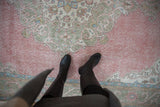 Distressed vintage Sparta carpet with worn pink pile, pale green and ivory scrolling florals.